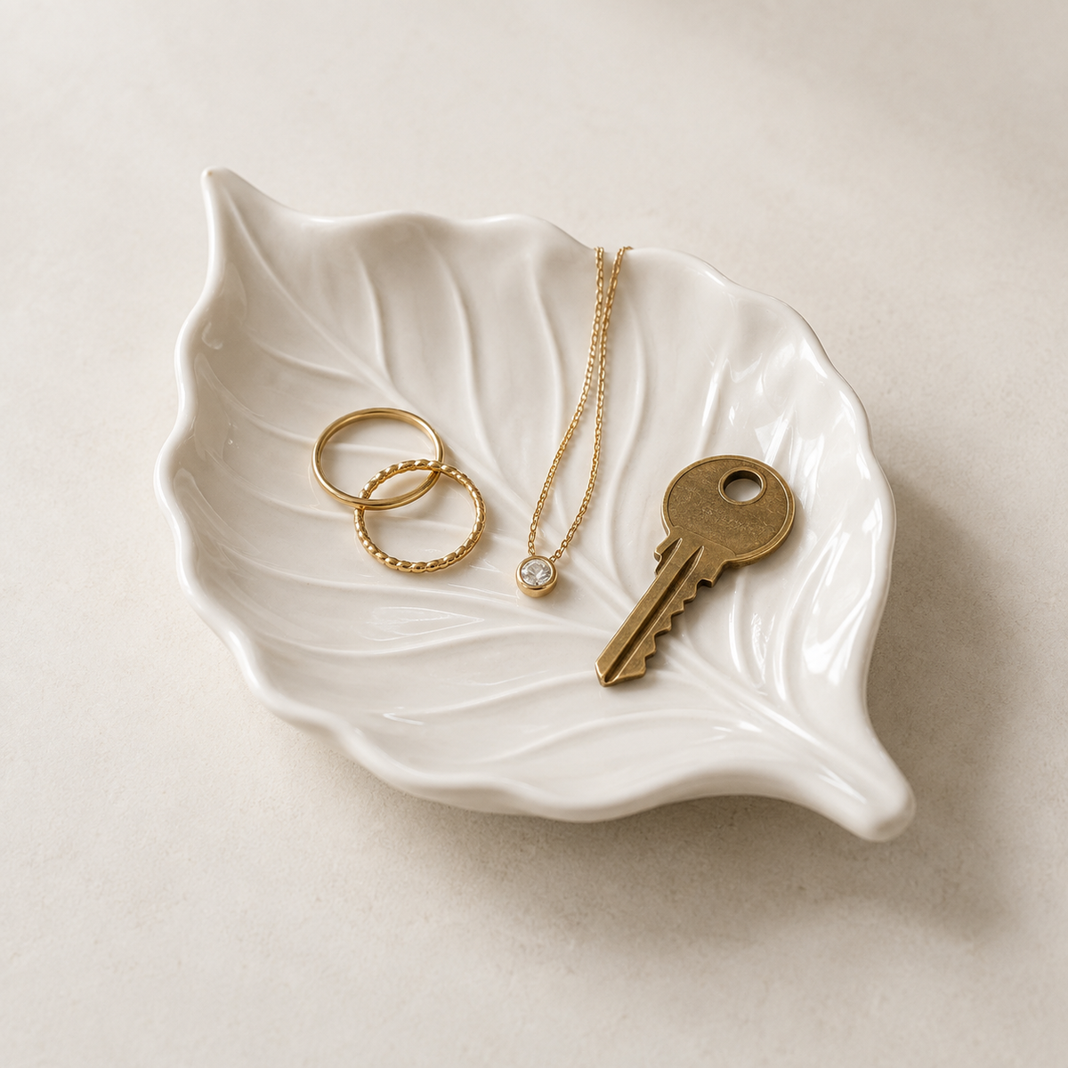 Milky-white leaf-shaped Yoaxo ceramic tray with jewelry and a key